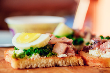 bruschetta, appetizer, canapes: fish tuna and spinach on toast of white bread, with egg on wooden Board