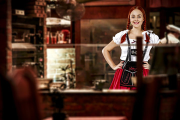 Young slim woman in bavarian clothes and her small business of bar 