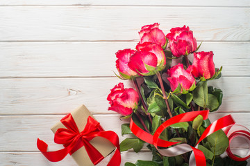 Red rose flower and present box on wooden table. 