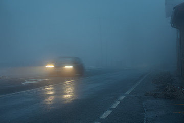 car at night on wet and slippery foggy road