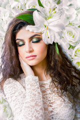 Obraz na płótnie Canvas Caucasian attractive woman with closed eyes on white lilies wall. Spring concept