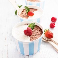 Chocolate vanilla ice cream with summer berries on white wooden board. Selective focus, copy space.