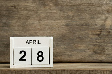 White block calendar present date 28 and month April on wood background
