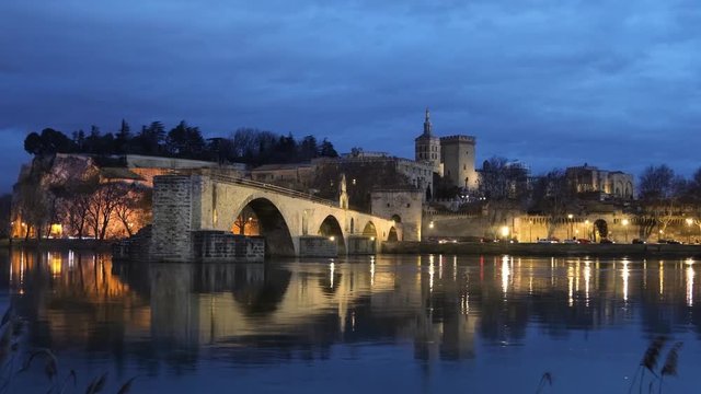 View on Pont d'Avignon 12th century bridge and city skyline reflecting in water at dusk in Avignon, Provence, France
