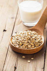 Oat flakes in wooden spoon with milk, blueberries for healthy breakfast, selective focus,