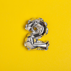 Silver foil number 2 celebration balloon on a bright yellow background