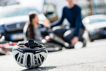 Close-up of a bicycling helmet fallen down on the ground after accidental collision between bicycle and a 4x4 car - obrazy, fototapety, plakaty