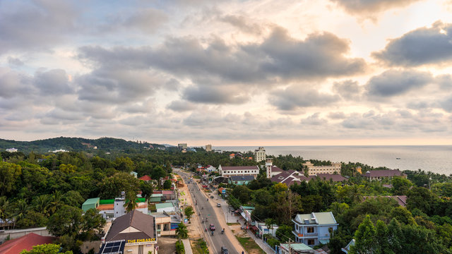 PHU QUOC, VIETNAM - NOVEMBER 18, 2017: Beautiful view from the high on town, road with motorbikes and sea on sunset
