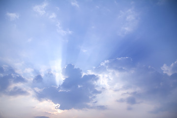 Sun shines through white clouds caused rays of light on a clear blue sky