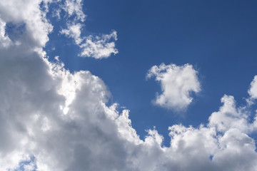 Obraz premium A large cumulus cloud and a small white cloud, separated from it on a blue sky.