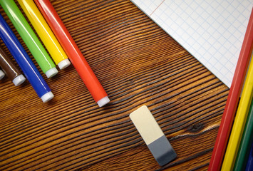 Fototapeta premium For study. Notebook, pen, eraser, colored pencils and colored markers on a dark wooden background