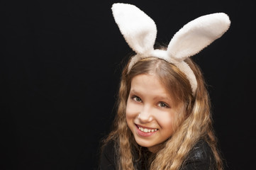 Young girl on a black background with white ears of a hare on her head