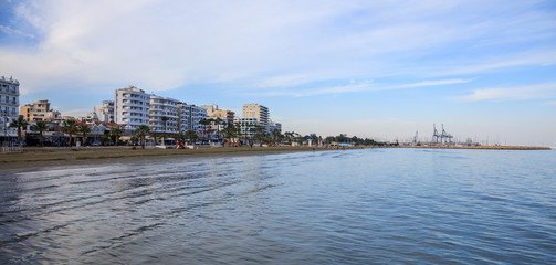 Obraz premium Finikoudes beach, Cyprus. Blue sky and clouds over city of Larnaca for background. Space, banner