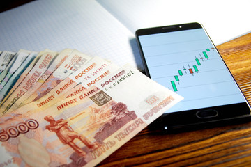 money. russian ruble. smartphone with exchange rates screen is on the notebook