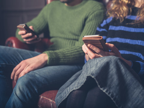 Man and woman on sofa using smart phones