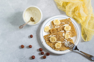 Thin russian pancakes with sour cream, bananas and hazelnuts