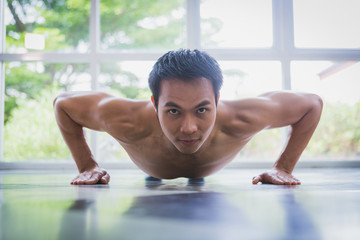 Fototapeta na wymiar Asian muscular guy doing push-ups exercise on the floor