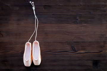 Ballet pointe shoes on dark wooden background top view copy space