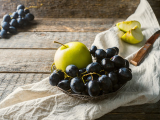 Still life grapes and apples in a vintage plate on rustic wooden background Copy space Selective focus