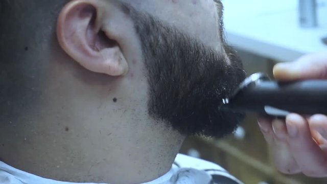 Barber shave with razor. Male barber trimming beard of client with clipper at barbershop. Close up of shaving beard man