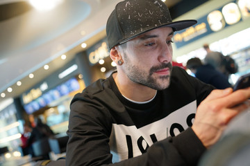 Obraz premium Trendy guy at the airport connected with smartphone