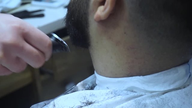 Barber shave with razor. Male barber trimming beard of client with clipper at barbershop. Close up of shaving beard man