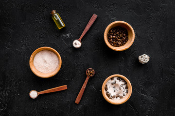 Cosmetics for skin care and relaxation. Chocolate brown spa salt on black background top view