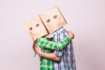 Love couple covering their faces with paper bag over white background