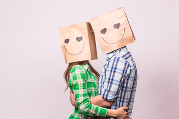 Love couple covering their faces with paper bag over white background