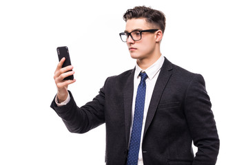 Naklejka premium Great news. Handsome young man using his phone with smile while standing against white background.