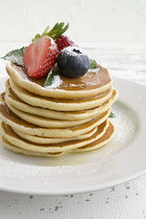 American pancakes with berries on a light background.
