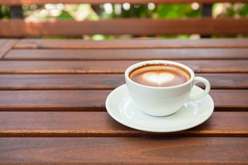 Cup of hot latte art coffee on wooden table.