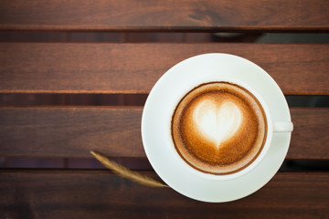 Cup of hot latte art coffee on wooden table.