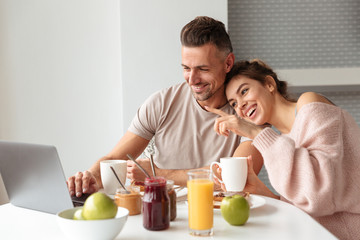 Happy loving couple having breakfast while sitting by the table