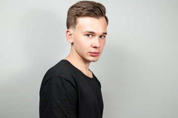  White young guy dressed in a black t-shirt on white background looking forward. Isolated.