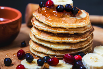Pancakes with honey, bananas, jam and berrieson a wooden plate Menu , restaurant recipe concept. Served in