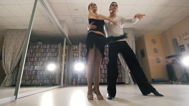 Young man and woman dancing and practicing Latin American dance in costumes in the Studio, slow motion, in action