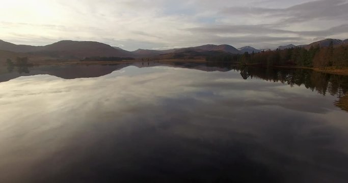 aerial footage of flying over a calm mirrorlike scottish loch in the remote highlands of scotland at loch tulla