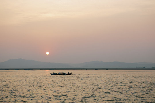 Sunset view of Irrawaddy River with local barge in the background and horizon