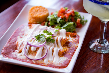 Enchilada plate in red sauce with Mexican rice and margarita with lime
