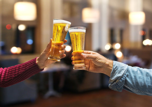 Beer glasses raised in a toast. Close-up hands with glasses.