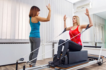 Fototapeta na wymiar Woman exercising on pilates reformer