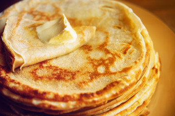 Russian Maslenitsa, Shrovetide, pancake week, carnival, shrove, pancake day. a stack of pancakes with butter upstairs on plate, on wooden background, close-up
