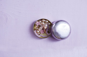 metal round box with jewelry  inside flat lay on a purple background