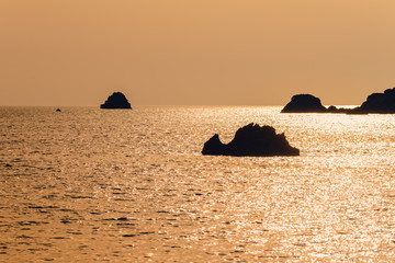Naklejka na ściany i meble Sunset over the sea, silhouettes of sea rocks on the horizon. Summer seascape. Corfu island, Greece