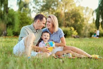 Fototapeta premium Happy family in nature. Parents with a child play in park.