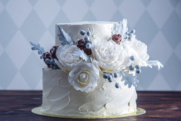 Delicate white bunk wedding cake decorated with an original design using mastic roses. Concept of...