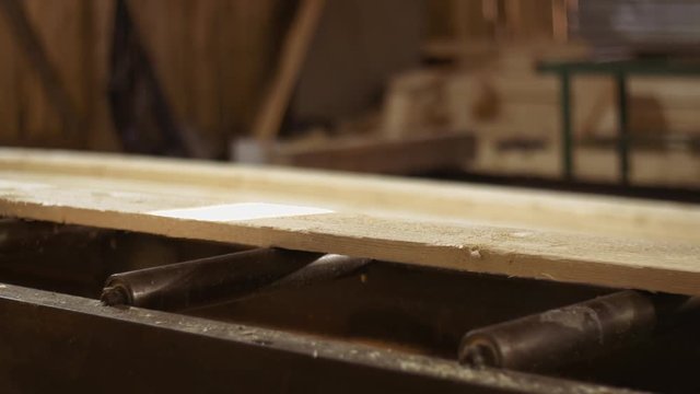 Wood board running into carpenter refiner machine at sawmill factory, lots of sawdust