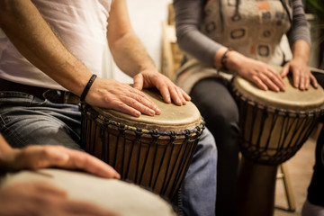 Fototapeta na wymiar Close up of hands on african drums, drumming for a music therapy