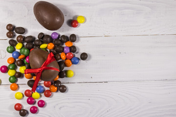 Easter composition with chocolate eggs on white wooden background